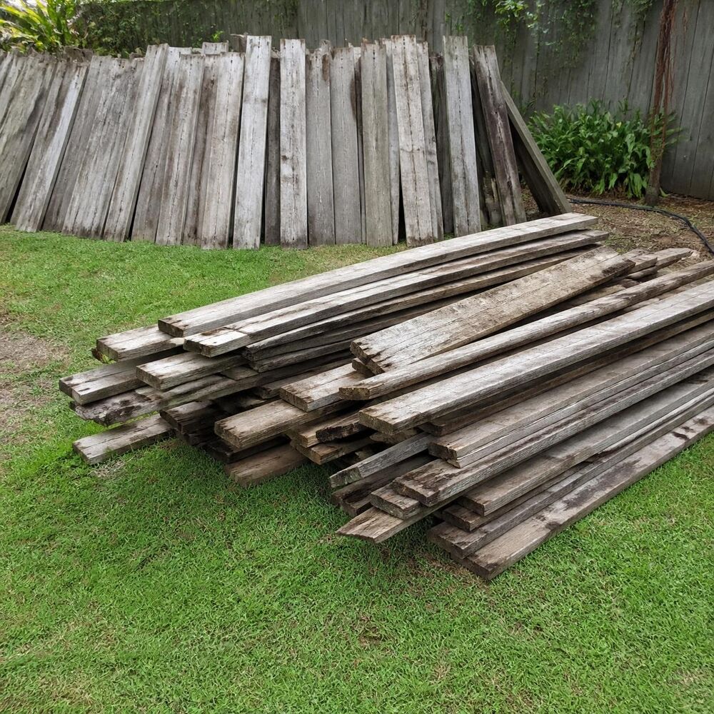 Old weathered decking boards and fence palings stacked on a lawn, ready to go