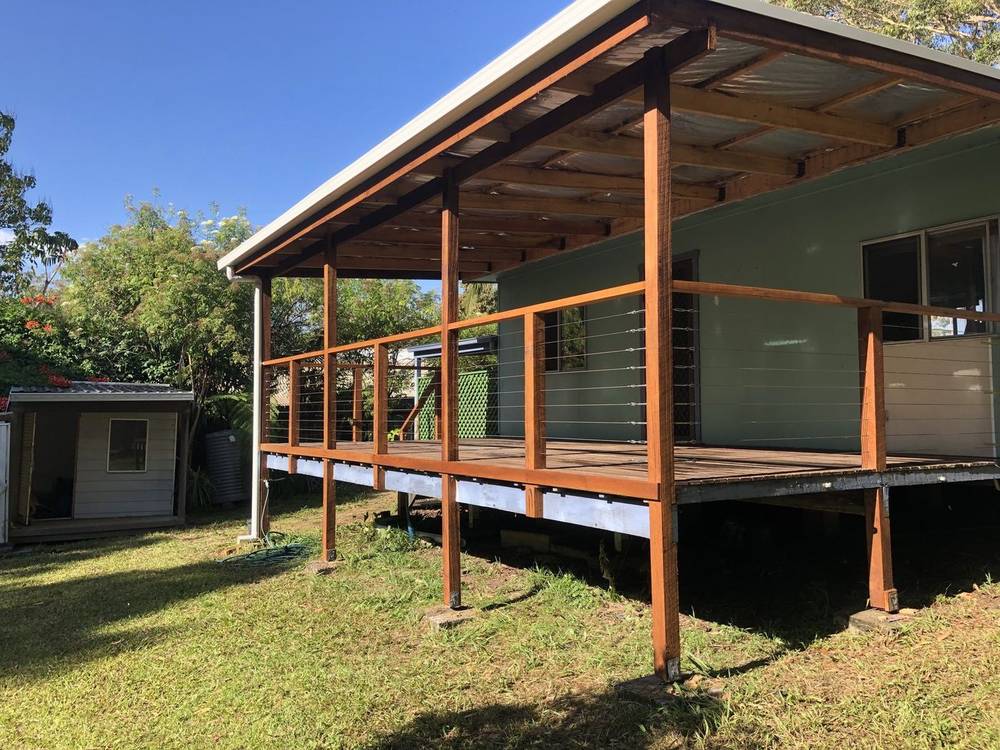 Raised covered deck with hardwood posts and a wire balustrade over a lawn