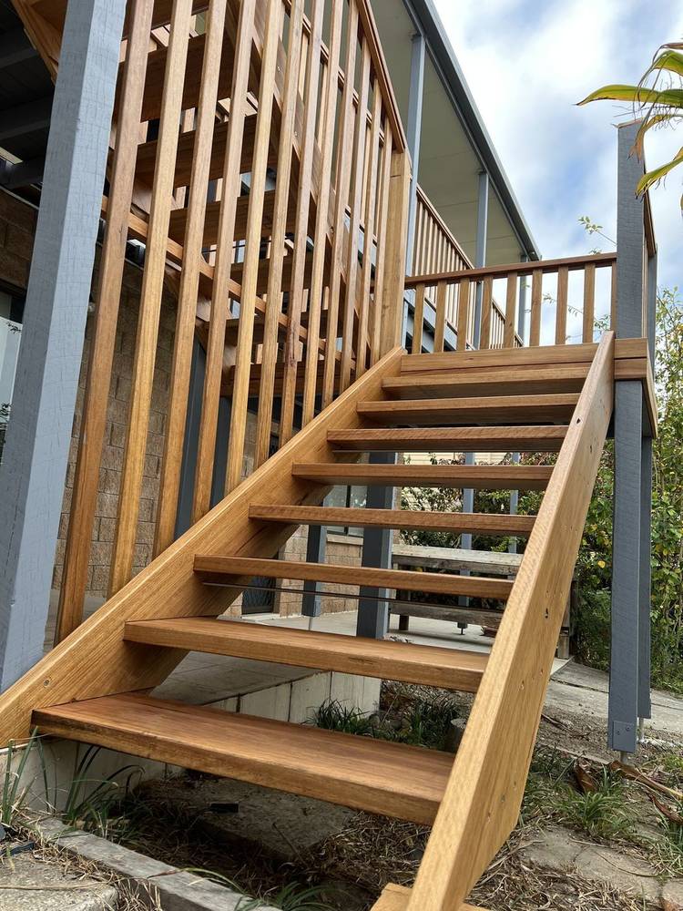 Timber stairs rising beside a vertical timber batten screen